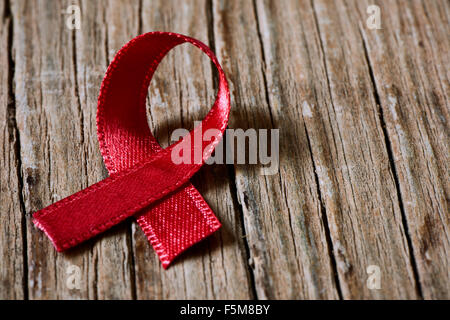 a red ribbon for the fight against AIDS on a rustic wooden surface Stock Photo