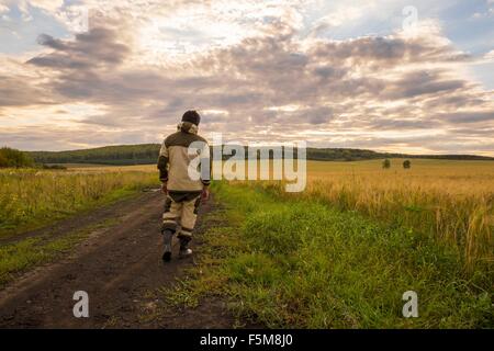 Mid adult man walking through field, rear view Stock Photo