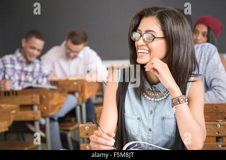 Female student, sitting at desk in classroom, smiling Stock Photo