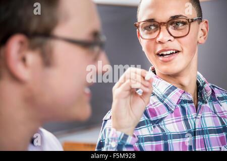 Two male students talking in classroom Stock Photo