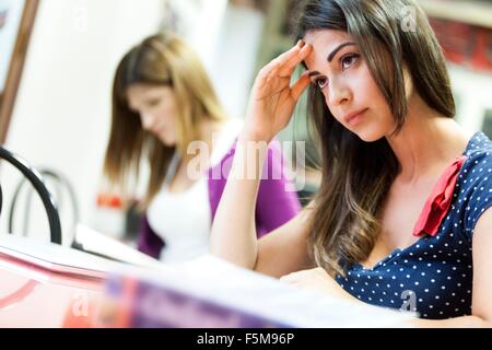 Young woman sitting at desk, studying, pensive expression Stock Photo