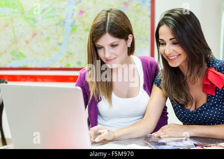 Two young women sitting together, studying, using laptop Stock Photo