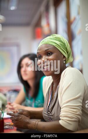 Mid adult woman, sitting at desk, smiling Stock Photo