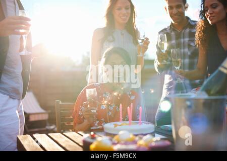 Friends at outdoor party blowing out candles on cake Stock Photo