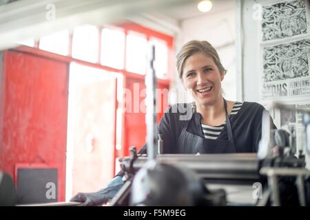 Portrait of female printer with traditional letterpress print machine in workshop Stock Photo