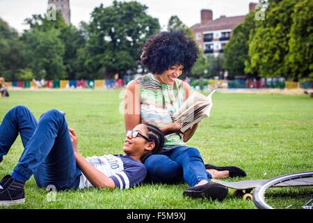 Boy and mother relaxing and reading book in park Stock Photo