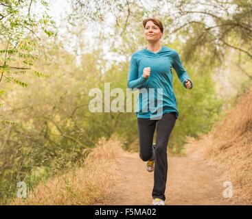 Mature woman running through forest Stock Photo