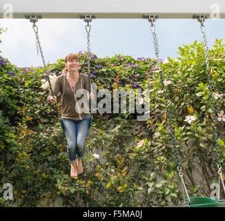 Smiling mature woman is swinging on a swing Stock Photo - Alamy