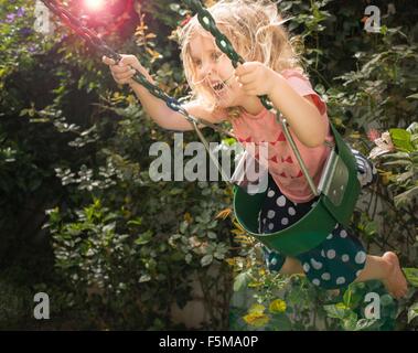 Young girl swinging in garden swing Stock Photo