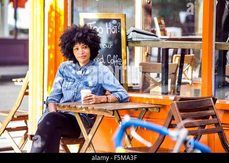 Mature woman drinking takeaway coffee and sidewalk cafe Stock Photo