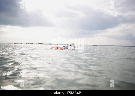 Senior woman on surfboard in sea, paddleboarding Stock Photo