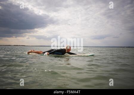 Senior woman on surfboard in sea, paddleboarding Stock Photo