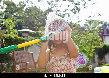 Girl with butterfly net over head in garden Stock Photo