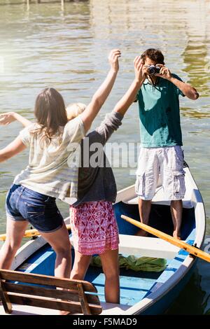 Young man in boat on lake photographing women Stock Photo