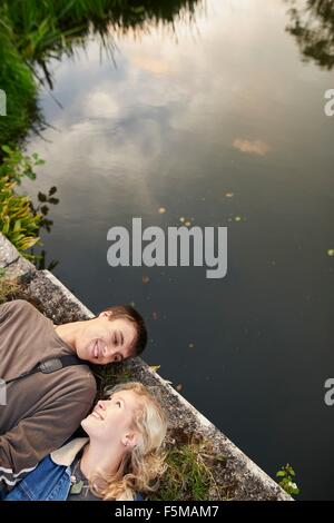 Overhead view of young couple lying on river footbridge Stock Photo