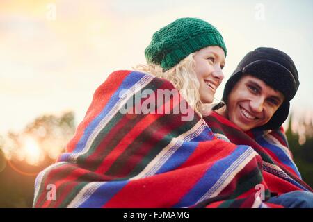 Portrait of romantic young camping couple wrapped in blanket Stock Photo