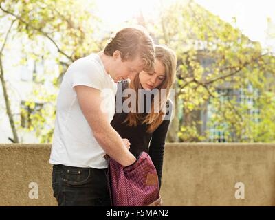 Young couple looking for something in bag, Melbourne, Victoria, Australia Stock Photo