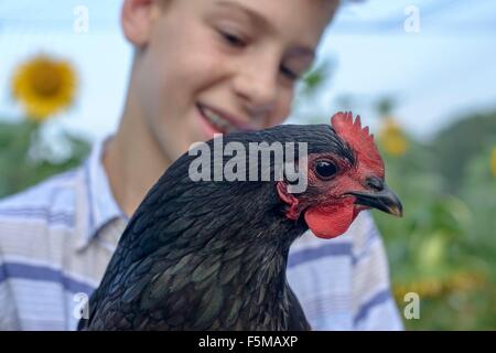 Close up portrait of boy in field holding hen Stock Photo