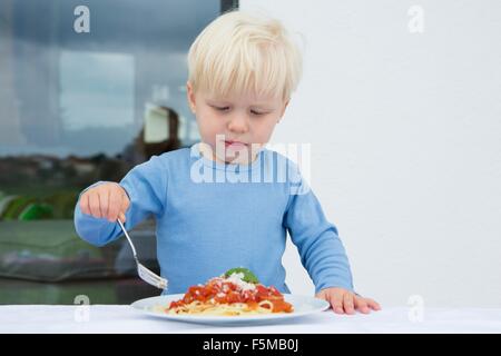 Male toddler eating spaghetti on patio Stock Photo