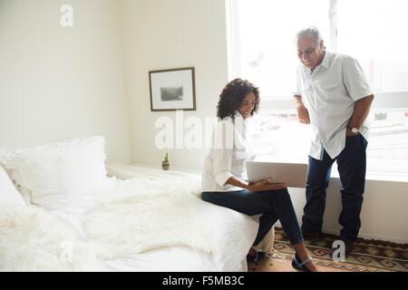 Senior man and wife looking at laptop in bedroom Stock Photo