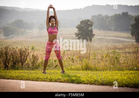 Young female runner warming up on rural park path Stock Photo