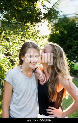 Two teenage girls whispering in garden Stock Photo