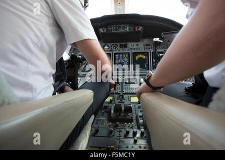 Male and female pilots in cockpit of private jet Stock Photo