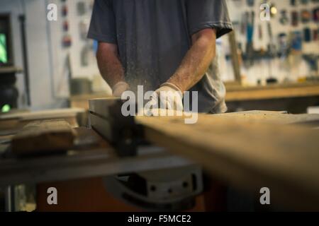 Wood artist in workshop, using woodworking machinery, mid section Stock Photo