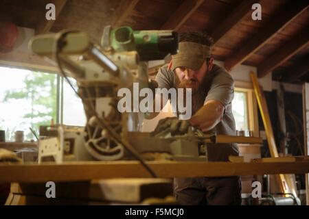 Wood artist using machinery in workshop Stock Photo