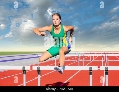 Runner jumping over hurdle on track Stock Photo