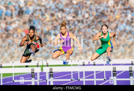 Runners jumping over hurdle on track Stock Photo