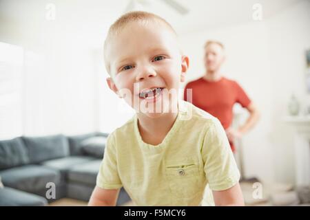Boy smiling in living room, father in background Stock Photo