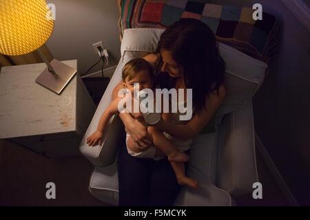 High angle view of mother in armchair feeding baby boy from baby bottle Stock Photo