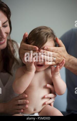Mother and father playing peek a boo with baby boy Stock Photo