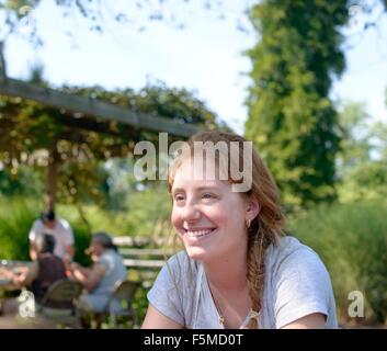 Red haired young woman outdoors looking away smiling Stock Photo