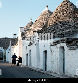 An elderly man and women chat outside the Trulli of Alberobello, Bari Province, Apuglia, Italy Stock Photo