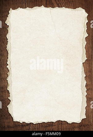Light brown torn paper is on old wooden board Stock Photo
