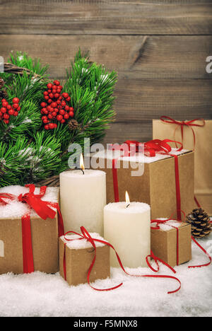 Christmas decoration with burning candles, gift boxes and christmas tree branches. Vintage style toned picture Stock Photo