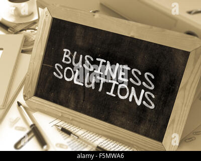 Business Solutions Handwritten by White Chalk on a Blackboard. Composition with Small Chalkboard on Background of Working Table Stock Photo