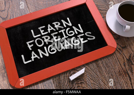 Hand Drawn Inspirational Quote - Learn Foreign Languages - on Small Red Chalkboard. Business Background. Top View. Stock Photo