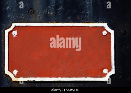 Old blank red metal sign on a dark background. Stock Photo
