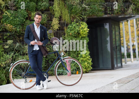 Businessman talking on cell phone sitting on his bicycle in city Stock Photo