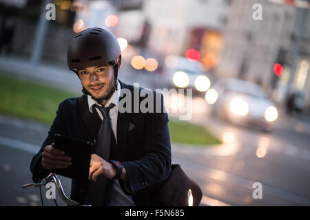 Man riding bicycle on city street using tablet and smart watch Stock Photo