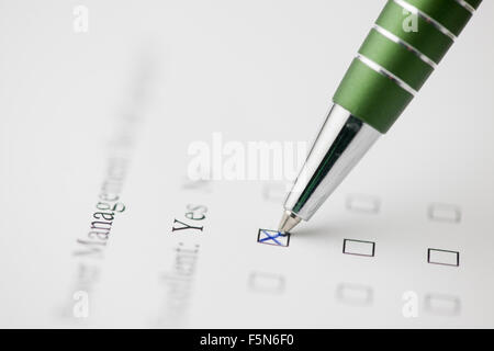 Close-up of a green pen a form on crossing with English writing "Yes" with very low depth of field Stock Photo