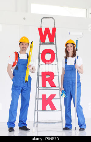 Two smiling professional workers with tools and WORK letters Stock Photo