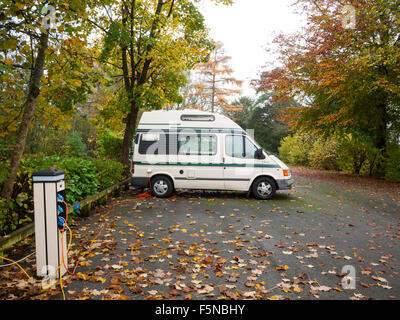 Camper van connected to hook-up on a campsite in autumn UK Stock Photo