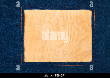 Frame for the text from a dark jeans fabric with the stitched lines of an orange thread, on a wooden background Stock Photo