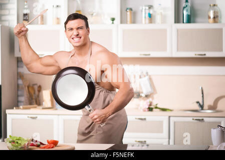 Cheerful young man posing with kitchen utensils. Stock Photo