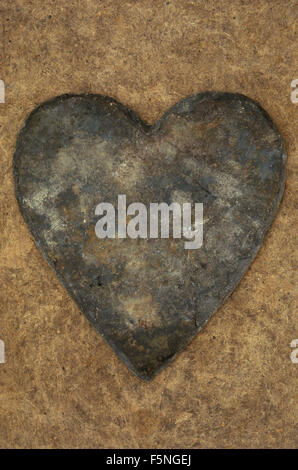 Heart-shaped grey slate with brown rust markings lying on antique board Stock Photo