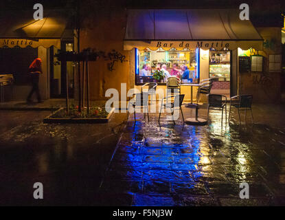 A group of men are sitting in a little local bar in Venice, Italy, during the evening while it is raining outside. Stock Photo